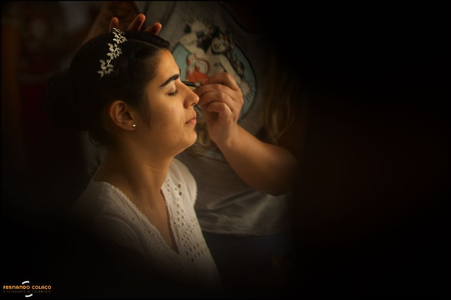 Bride's face amid blurred guests when she was in the make up, viewed by the wedding photographer in Alentejo.