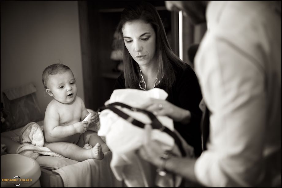 Parents choosing clothes for their baby boy to wear for the christening, with him watching.