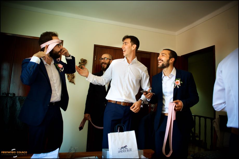 One of the groom's friends puts his tie on his head and the others laugh.