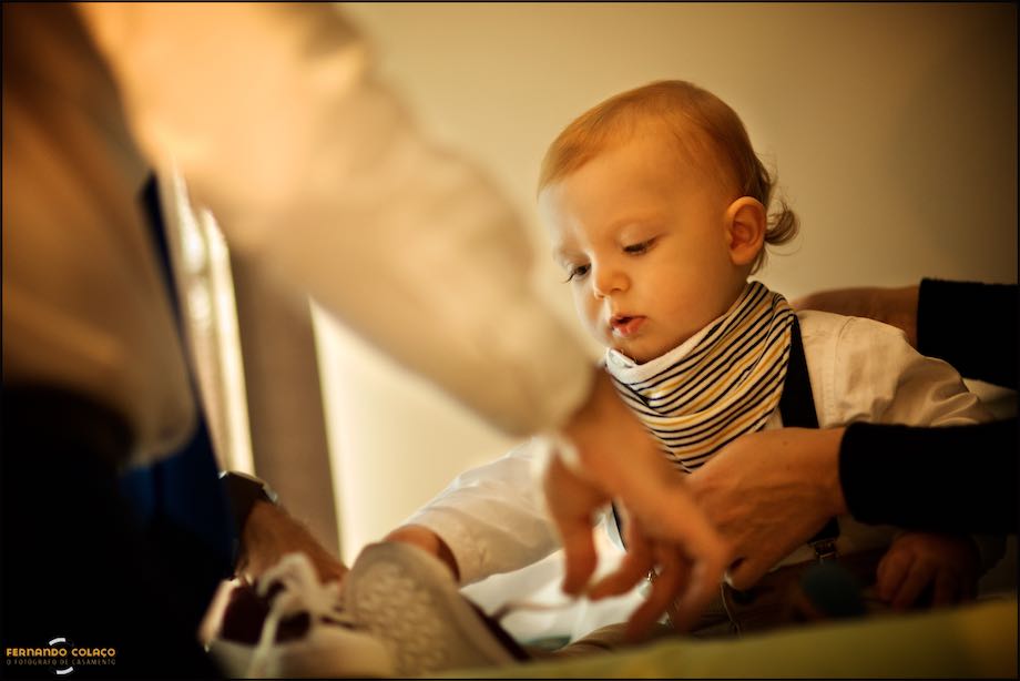 Baby sitting to put on his shoes before going to the christening, captured by the baptism photographer in Lisbon.