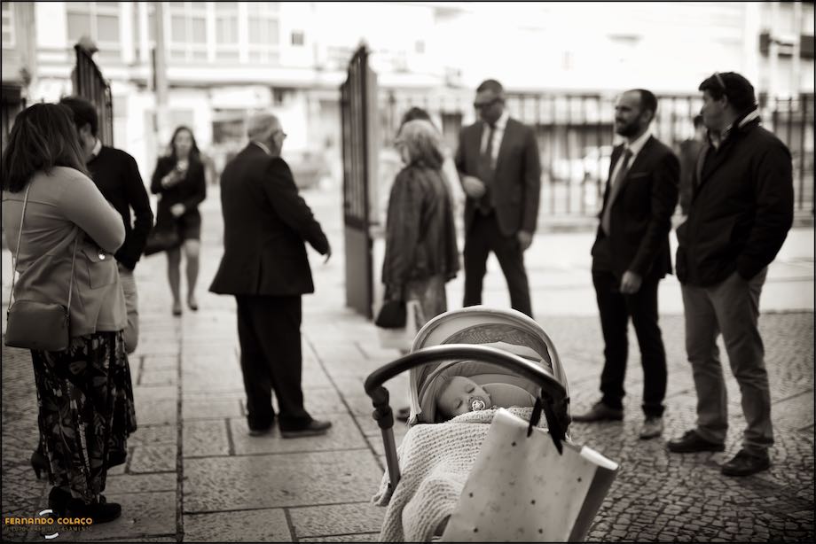 Baby sleeping in the stroller with guests, from baptism, in the background, like the baptism photographer saw him.