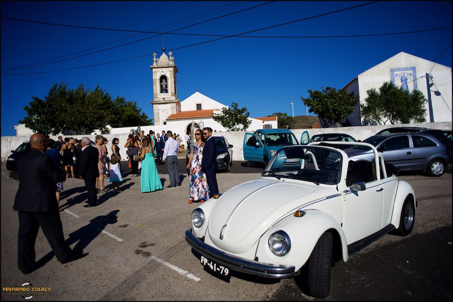 Church square with guests of the bride and groom and VW Beatle car.