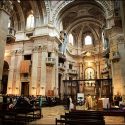 Interior view of the Mafra Basilica with the bride and groom and wedding guests in perspective by the wedding photographer in Portugal.