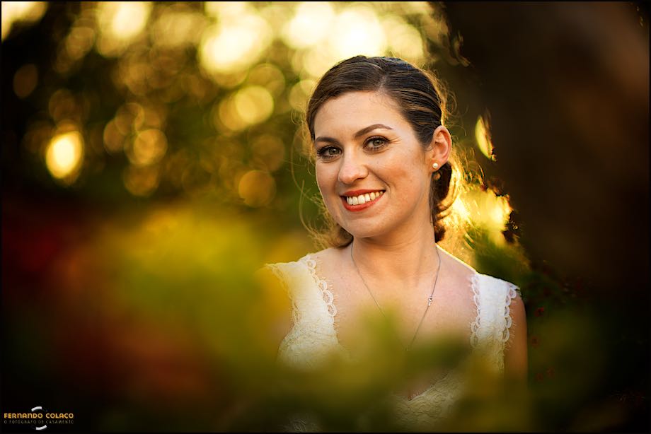Bride between blurred trees, under a golden afternoon light.