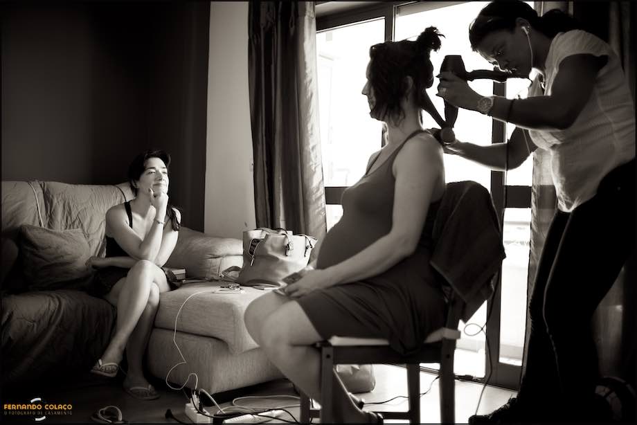 Two women guest of the wedding, seated, talking when one is being hair dressed.