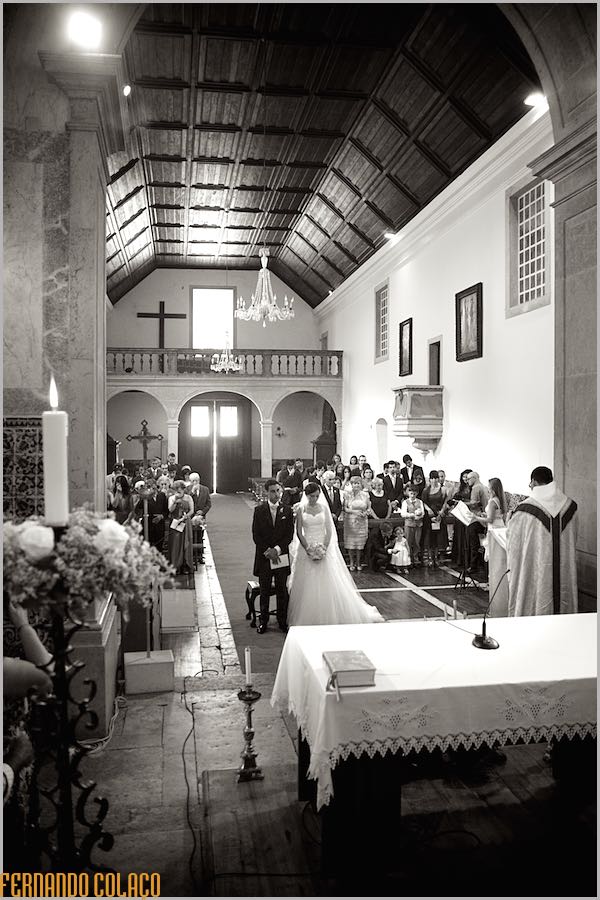 The interior of the Church of Nossa Sra. da Assunção in Enxara do Bispo with the bride and groom, the priest and, behind them, all the family members and wedding guests.