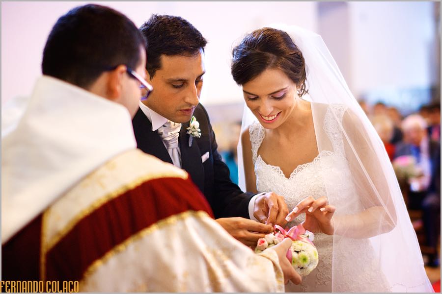 Next to the priest, who holds the base, the groom and bride remove the rings for the ceremony.