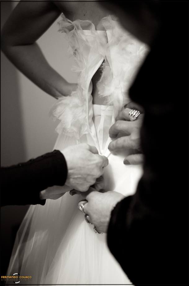 Hands finishing, in the back, the bride's dressing.