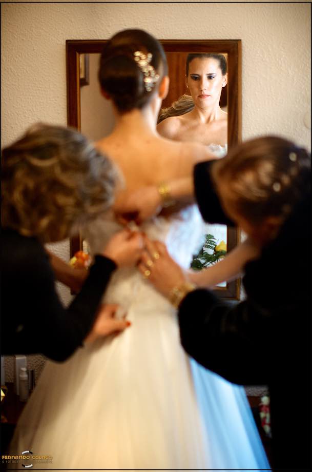 Bride in the mirror being helped to dress the dress