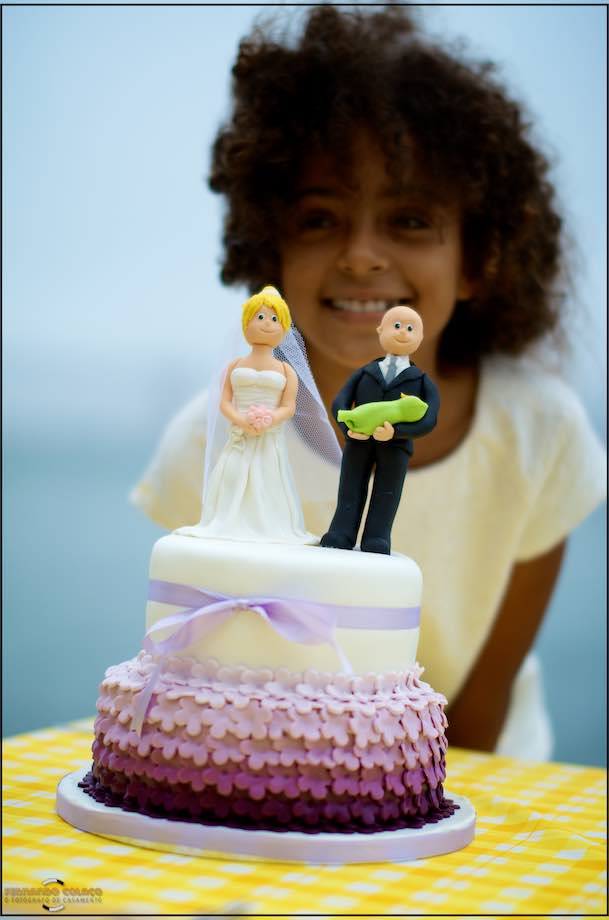 The bride's cake with a couple of engaged dolls on top and the couple's daughter behind, out of focus.