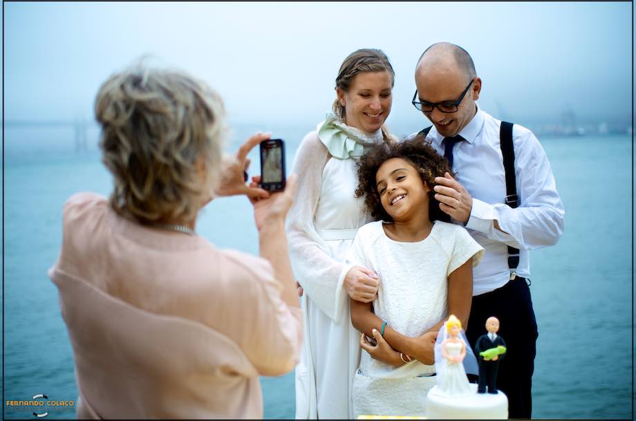 A friend of the newly married couple takes a picture of them with her daughter in their midst, during the wedding party at Ponto Final in Cacilhas.