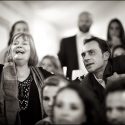 A girl sitting on the floor, among other guests at the wedding at Quinta da Cascata, carefully watches a video about the newly married couple.
