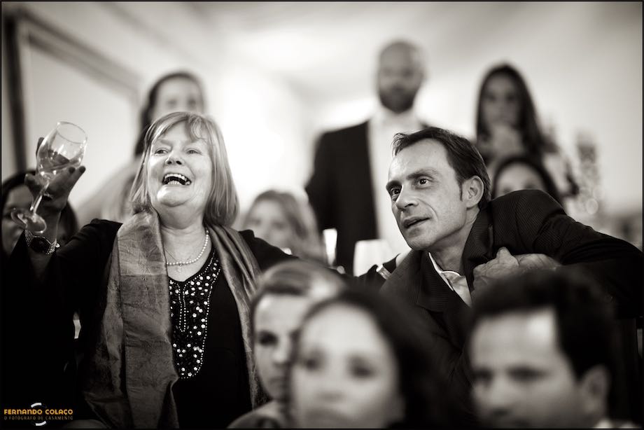 A girl sitting on the floor, among other guests at the wedding at Quinta da Cascata, carefully watches a video about the newly married couple.