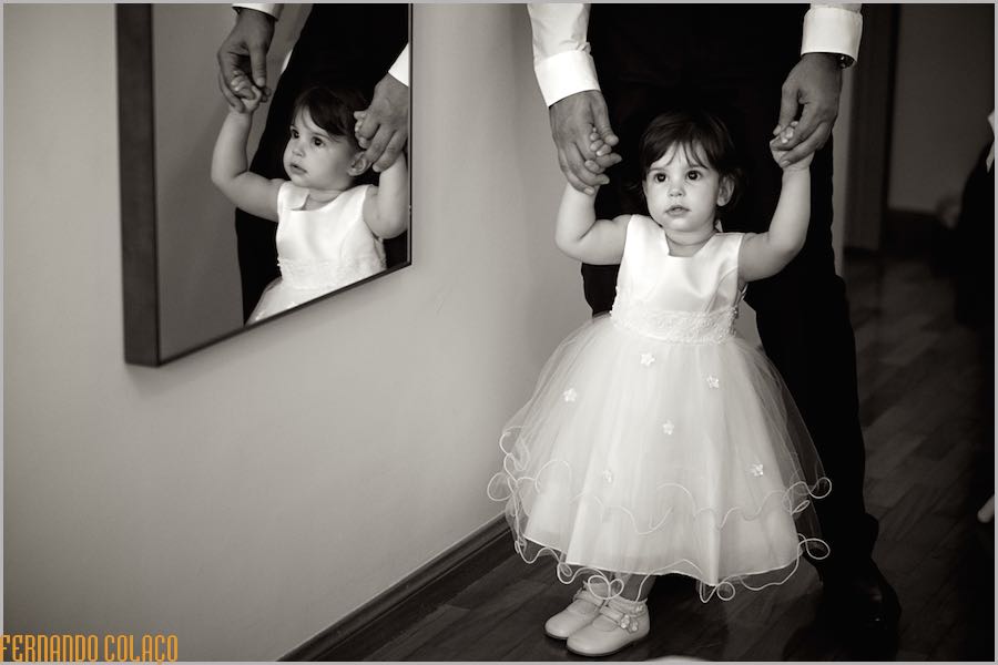 The youngest daughter of the couple to be married, held by two hands and reflected in a mirror.