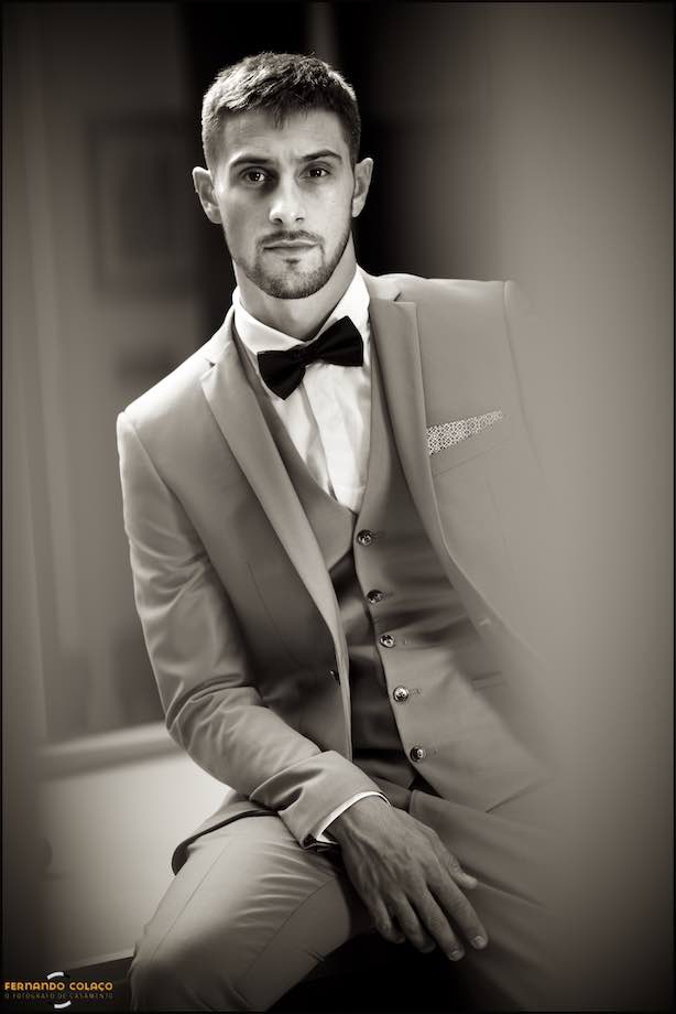 The groom, seated, in a portrait session before leaving for the wedding ceremony.
