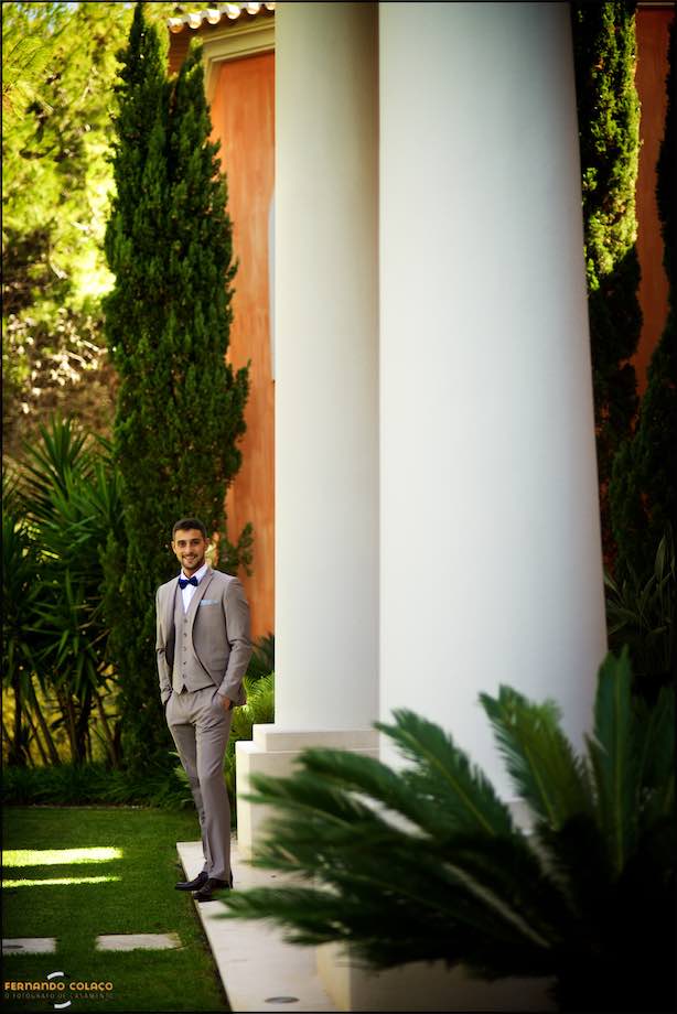 Groom near two huge columns in the garden of his house.