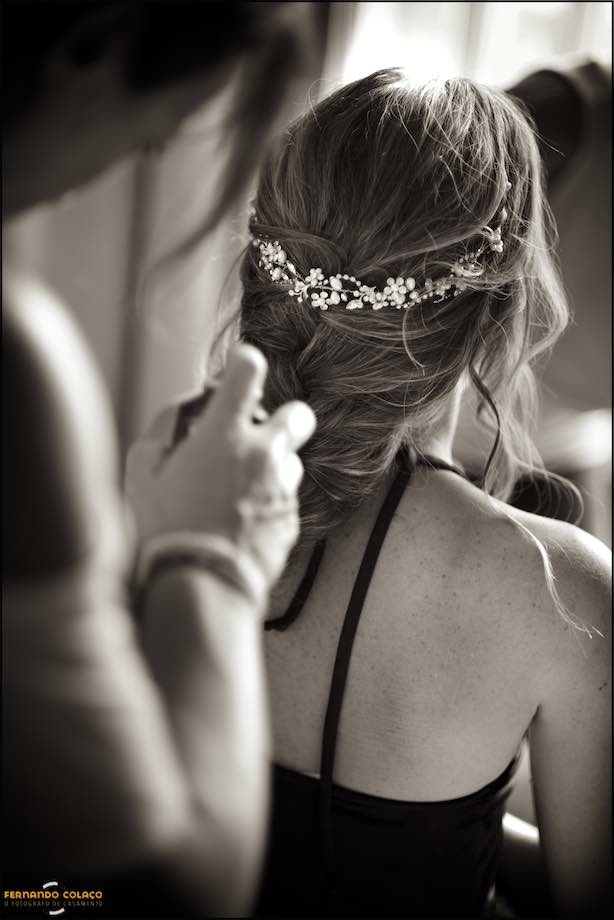 Bride getting her hair done, seen from behind with tiara on her head.