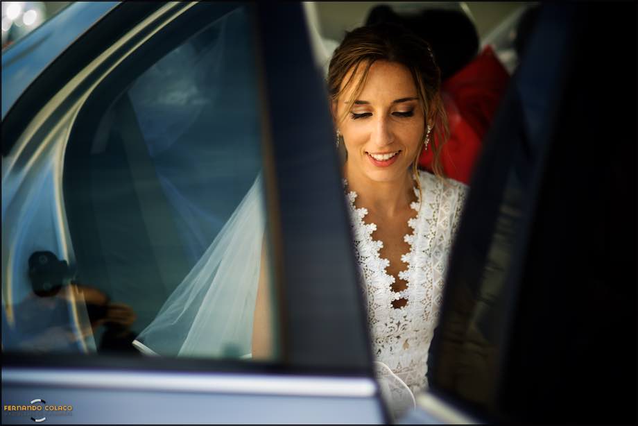 Inside the car the bride looks down as she adjusts her dress inside and prepares to leave for the wedding reception.