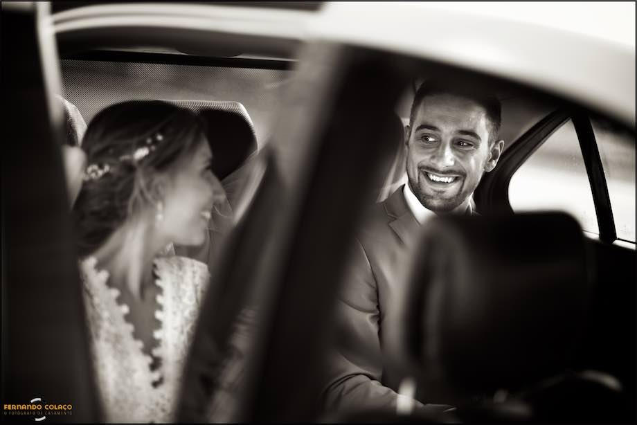 The groom laughs at the bride as she gets into the car that will take them to the wedding reception.