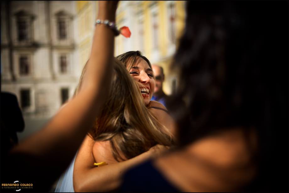 Happy bride hugs a girl friend who went to her wedding at Basílica de Mafra, captured by the wedding photographer in Lisbon, Portugal.