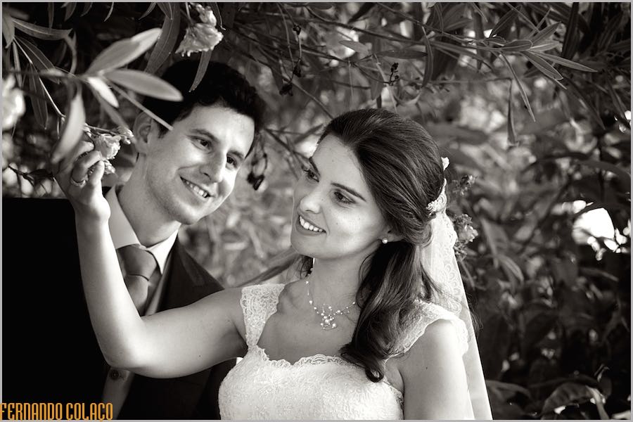 Underneath an oleander tree at Quinta do Louredo in Évora, the bride and groom smile as they look at each other.