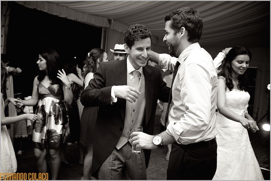 In the midst of other guests, the groom embraces a friend during his wedding reception at Quinta do Louredo in Évora.