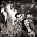 The couple, together and looking straight ahead, with horses, out of focus, behind them during the elopement session with the wedding photographer in Lisbon, Portugal.