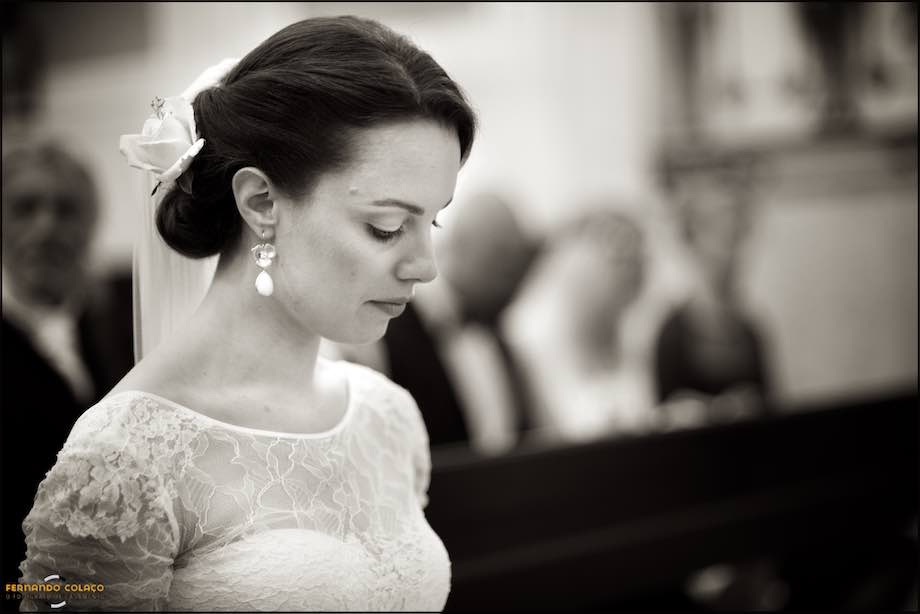 Bride lowers her head as she listens to the priest, at the wedding ceremony.