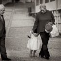 A girl hides behind her grandmother when she, also, arrives with her grandfather at the church, for the ceremony, by the wedding photographer in Lisbon, Portugal.