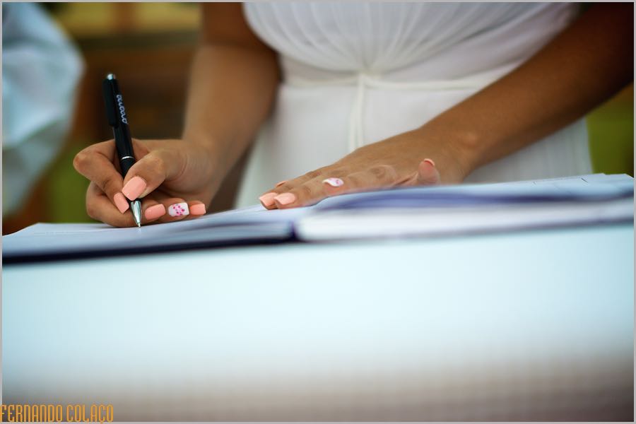 As mãos da noiva assinando o documento oficial, numa composição do fotógrafo de casamento no Algarve.