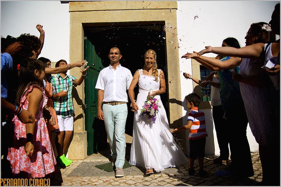 Os noivos saem da igreja depois da cerimónia  enquanto os convidados lhes atiram flores e arroz.