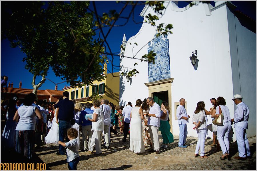 Os convidados do casamento junto dos noivos à porta da Igreja, no fim da cerimónia do casamento, pelo fotógrafo de casamento no Algarve.