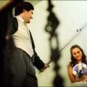 O noivo olha para noiva sentada nas escadas do Café paris em Sintra, antes de entrarem na sala de refeições para o jantar do casamento, conforme os viu o fotógrafo de casamento.