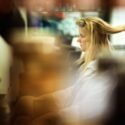 The bride at the hairdresser as her hair is straightened, seen in profile in a mirror by the wedding photographer in Lisbon, Portugal..