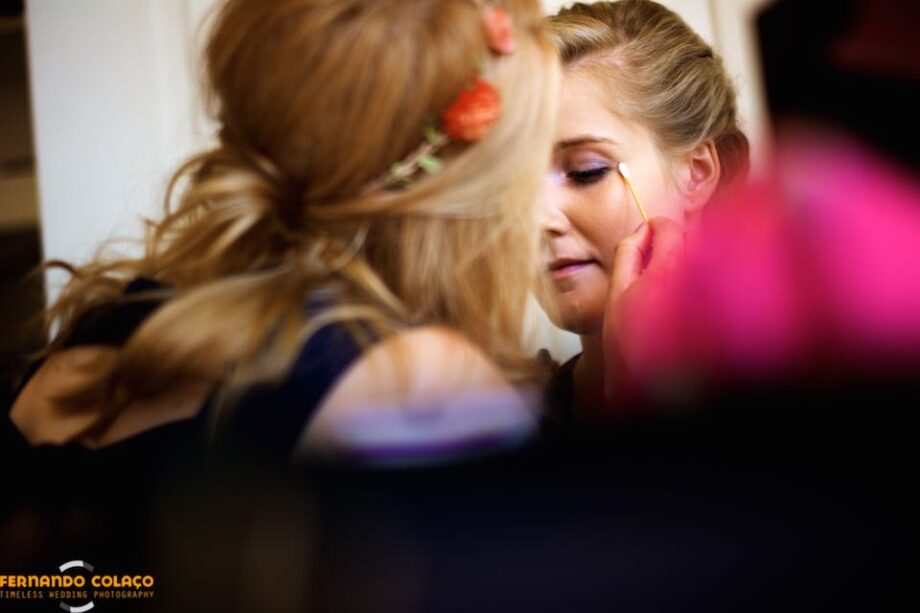 Bride's face in a mirror, already at home, when her sister retouches her make-up.