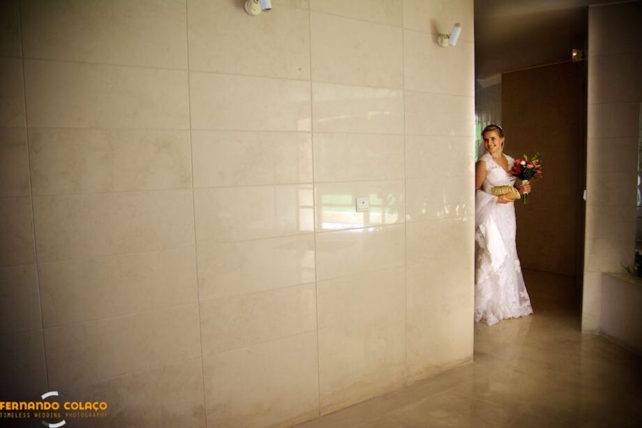 The bride appears in the exit hall of the building to get into the car that will take her to the ceremony in the church.