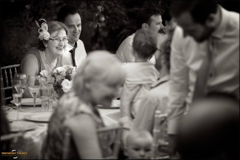 A wedding guest plays playfully with a baby on her father's lap,.