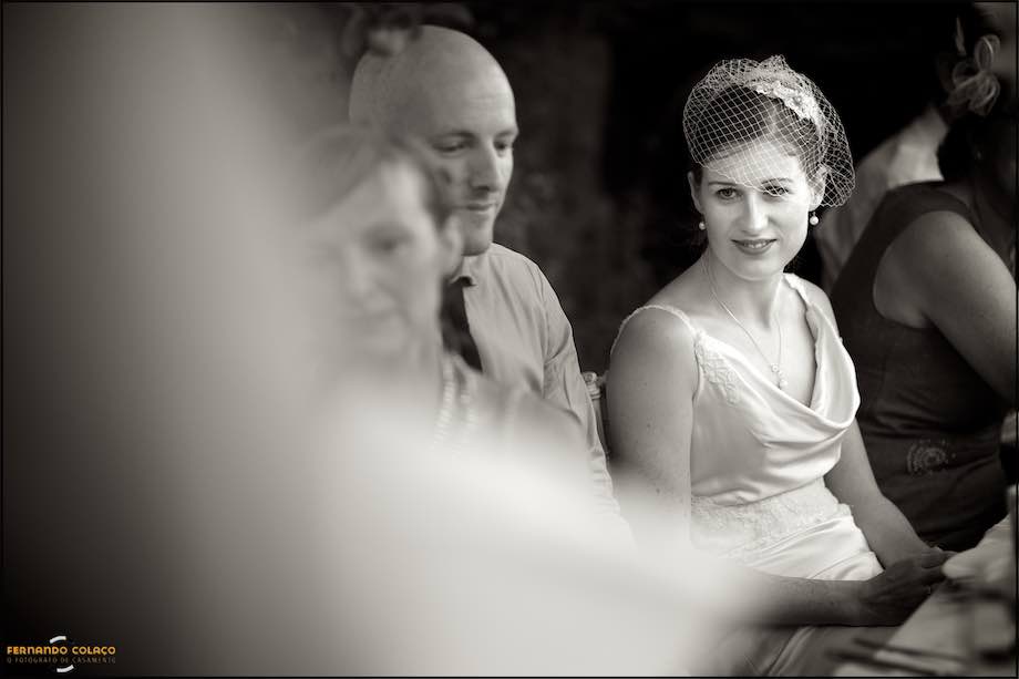 The bride, seated next to the groom, listens to someone giving a speech at her wedding party in Monchique, Algarve.