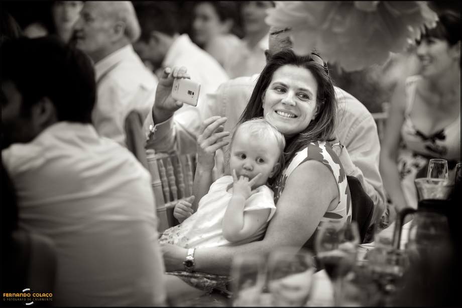 Baby girl on her mother's lap smiling at someone at her wedding party in Monchique.