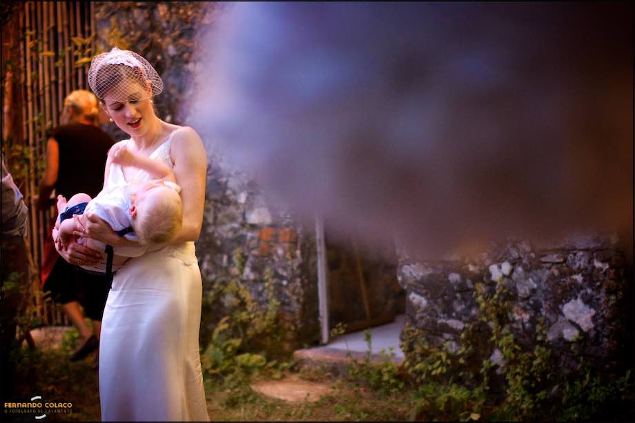 The bride plays with her baby on her lap.