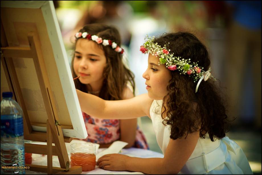 Two girls paint a canvas in the convivial afternoon at Quinta da Serra in Sintra, by the wedding photographer.