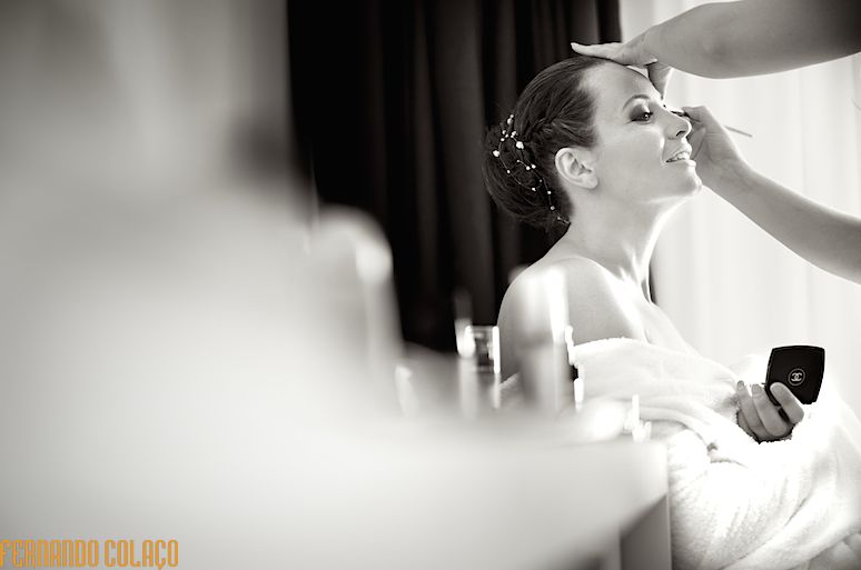 Sentada junto de uma janela, a noiva a ser maquilhada,  numa composição do fotógrafo de casamento em Leiria.