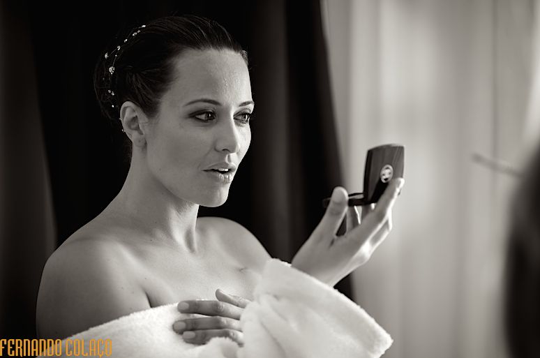 A noiva olha para um espelho de bolso, verificando o resultado da maquilhagem, vista pelo fotógrafo de casamento em Fátima, Leiria.