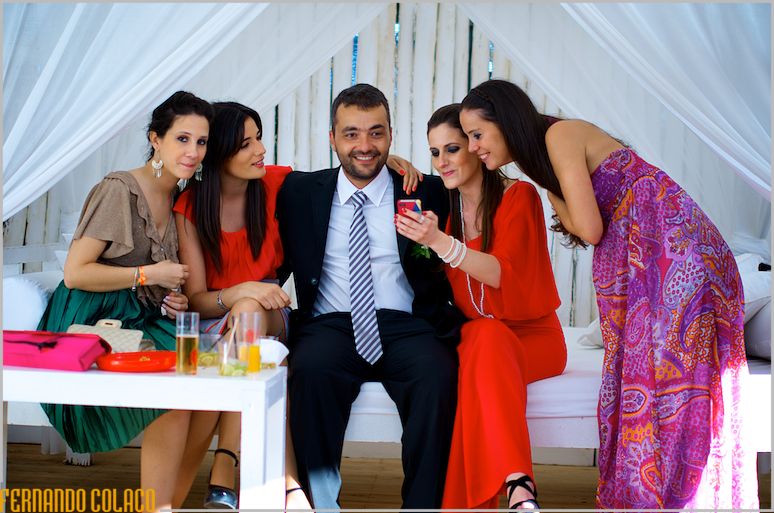 O noivo, sentado no Waikiki bar na Praia da Sereia, recebe carinhos das suas amigas que o felicitam pela cerimónia, captados pelo fotógrafo de casamento em Lisboa.