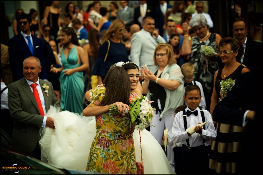Na frente dos seus convidados, a noiva abraça uma amiga que a felicita pela cerimónia.