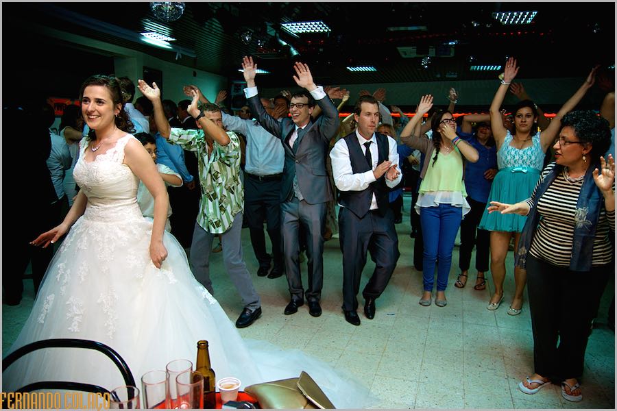 A noiva na frente de um grupos de convidados com o noivo que executam uma dança em sua homenagem, vistos pelo fotógrafo de casamento em Évora.