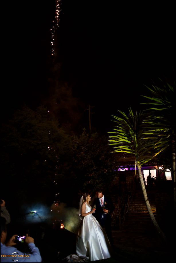 Restos de luz do fogo de artifício caem perto do local onde o noivo e a noiva cortaram o bolo do casamento e ofereceram aos seus convidados na Quinta do Castro, vistos pelo fotógrafo de casamento em Lisboa.