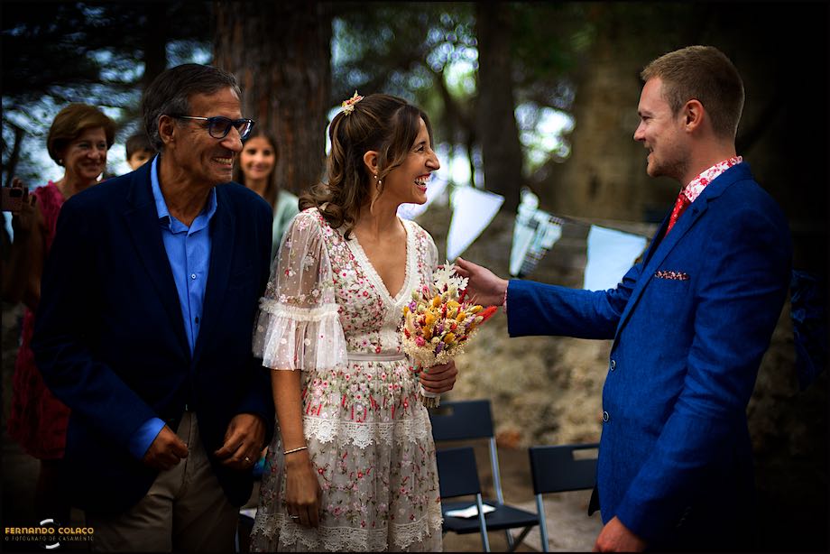 O noivo recebe a noiva e o pai que riem de satisfação, para começar a cerimónia do casamento no Castelo de S. Jorge em Lisboa, conforme os captou o fotógrafo de casamento.