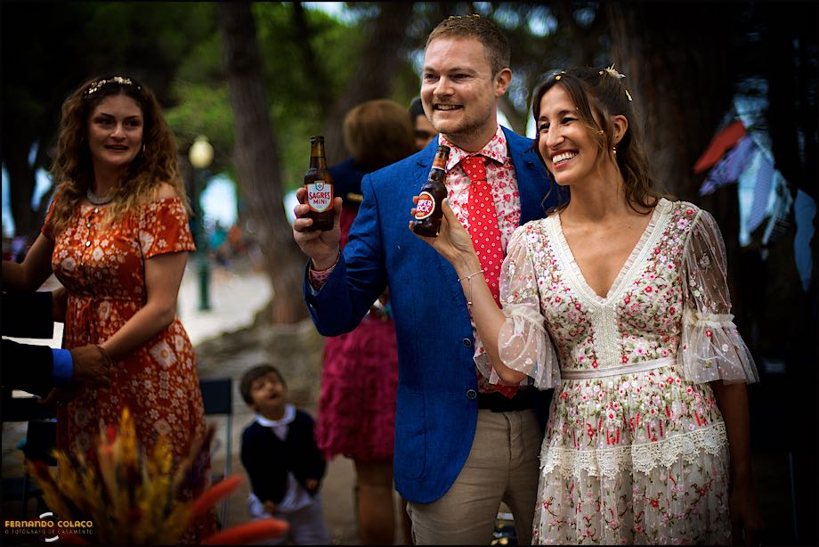 O noivo e a noiva, ao lado um do outro, fazem um brinde, com duas cervejas, a todos os que estiveram presentes na cerimónia do casamento no Castelo de S. Jorge em Lisboa.