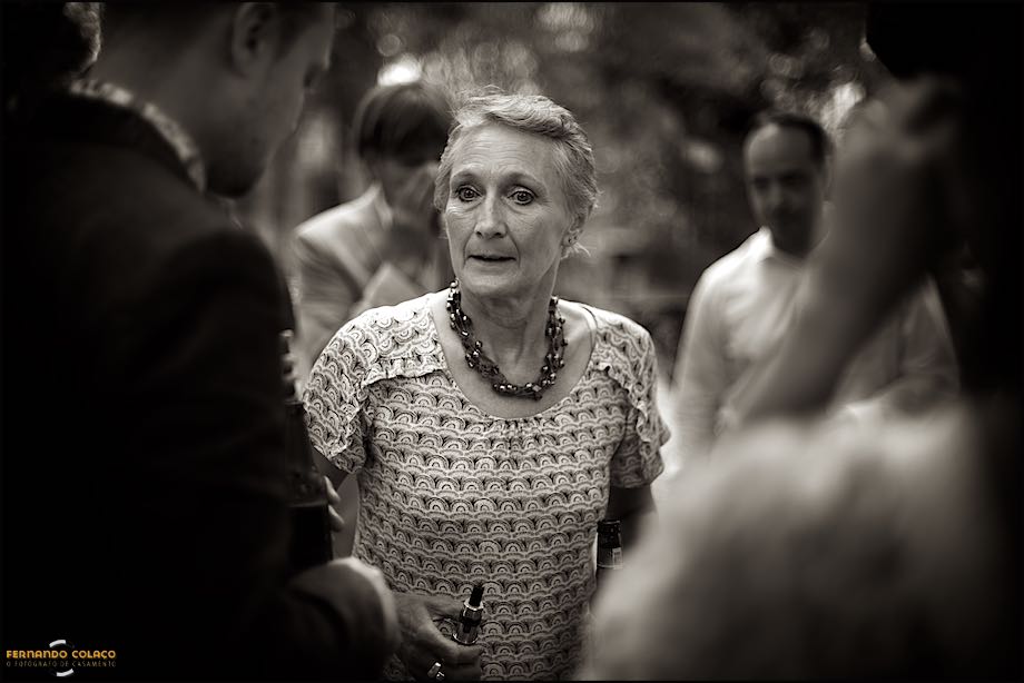 A mãe do noivo conversa com ele, desfocado, no tempo de convívio depois da cerimónia do casamento ter terminado, vistos pelo fotógrafo de casamento em Portugal.